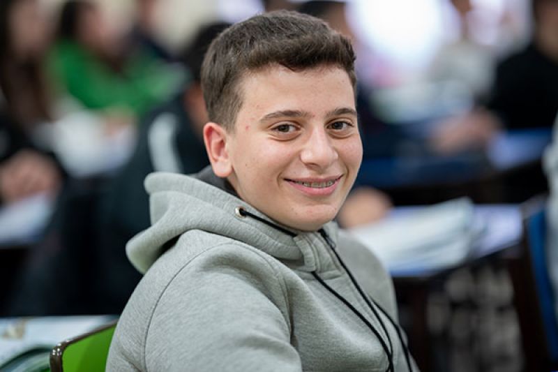 Ein Junge im Klassenzimmer lächelt in die Kamera