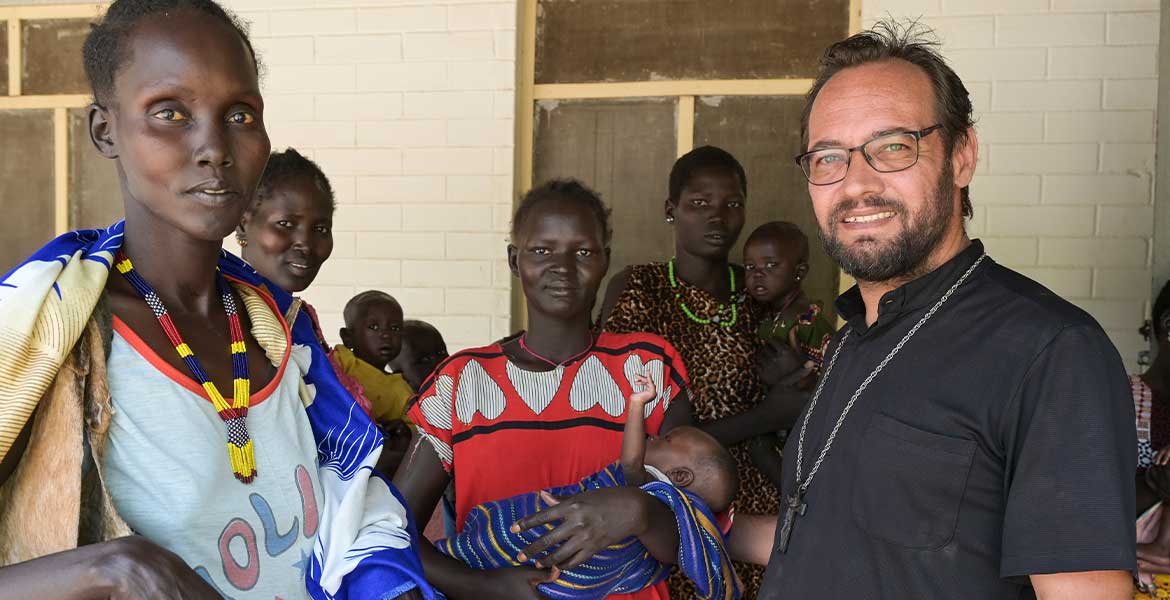 Zu sehen ist eine Gruppe von Menschen aus dem Südsudan, rechts vorne im Bild steht missio-Projektpartner Christian Carlassare, Bischof von Bentiu.