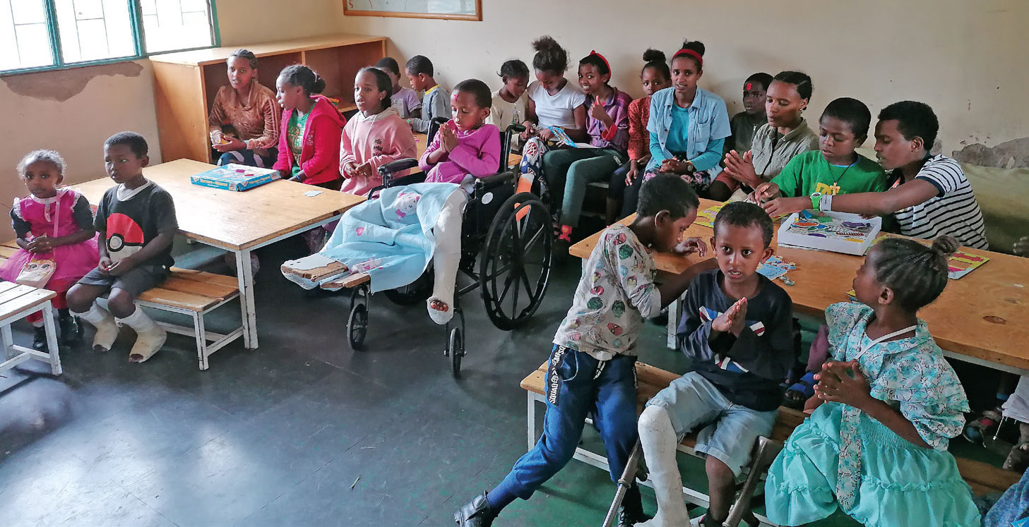 Rund 20 Kinder aus Äthiopien sitzen in einem Klassenraum an Tischen und dazwischen und blicken nach vorne Richtung Kamera.
