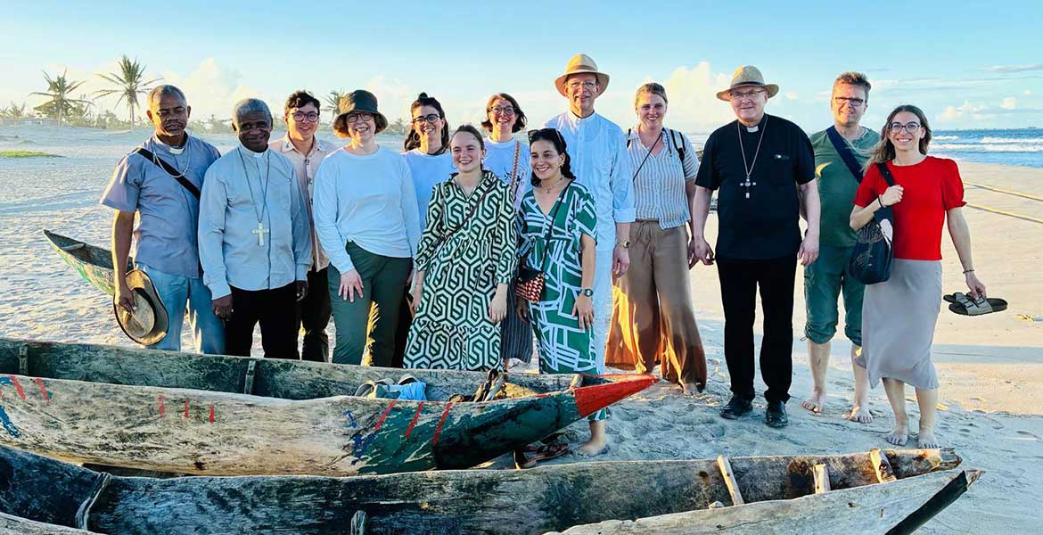 Gruppenfoto der missio-Delegation auf einem Strand in Madagaskar. Im Vordergrund mehrere einfache Boote aus Holz.