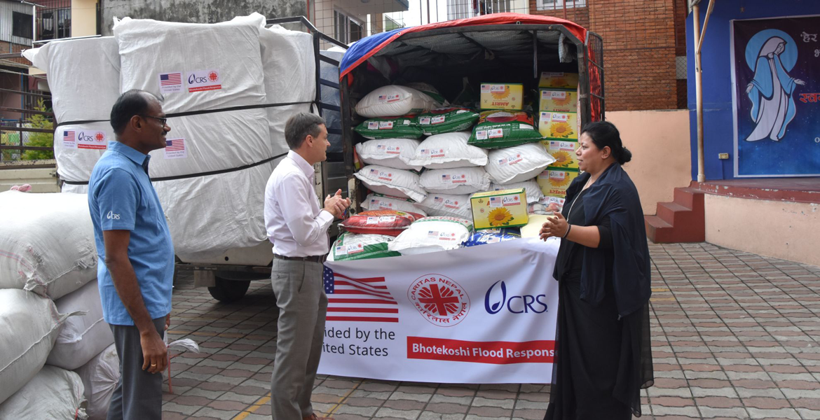 Ein kleiner Lastwagen vollbeladen mit Lebensmitteln steht auf dem Hof der Caritas Nepal in Kathmandu. Davor zwei Helfer der Caritas und Caritas-Direktorin Schwester Cecilia.