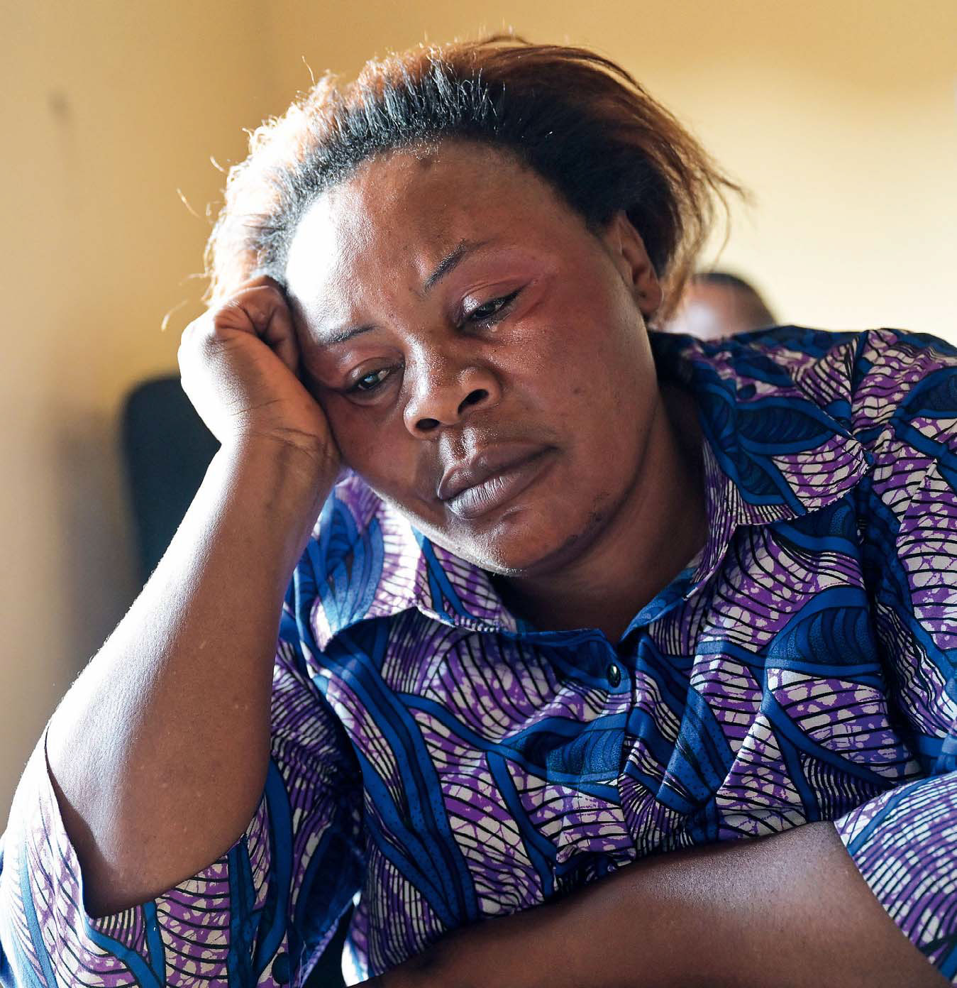 Constance Kahindo stützt den Kopf in die rechte Hand und blickt in sich gekehrt nach unten.
