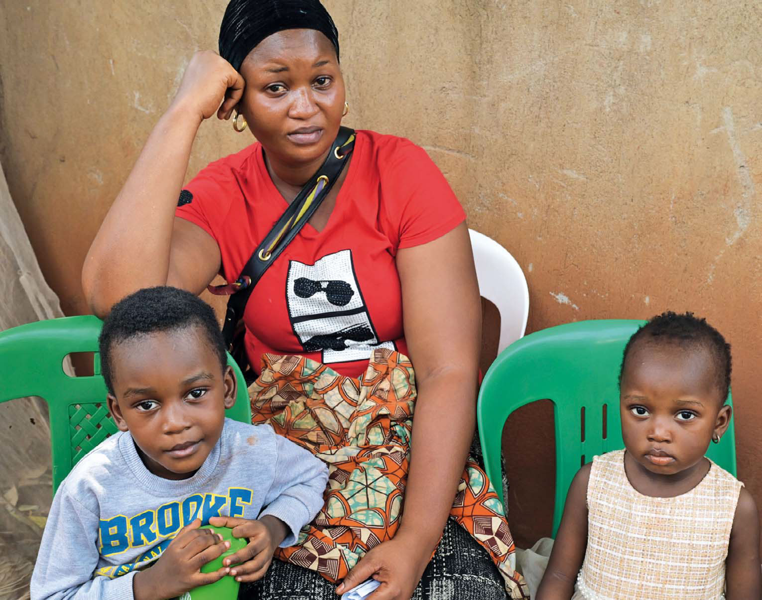 Esther Lwamba sitzt auf einem Plastikstuhl. Vor ihr: zwei ihrer vier Kinder.
