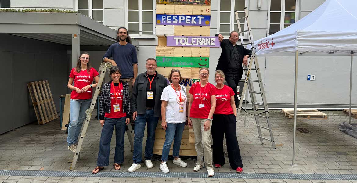 Ein Gruppenfoto mit missio-Mitarbeitenden und Präsident Monsignore Huber rund um einen Holzturm der missio-Demokratieaktion.