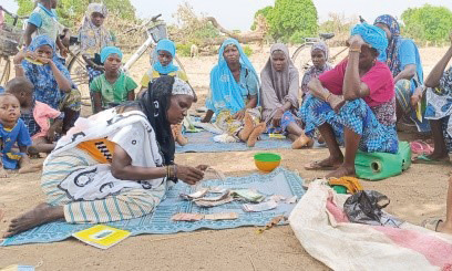 Mehrere Frauen sitzen in Burkina Faso auf sandigem Boden. Auf einem ausgebreiteten Tuch zählt eine der Frauen Geldscheine. Die anderen Frauen - alle in traditioneller Kleidung aus Tüchern - beobachten sie dabei. 