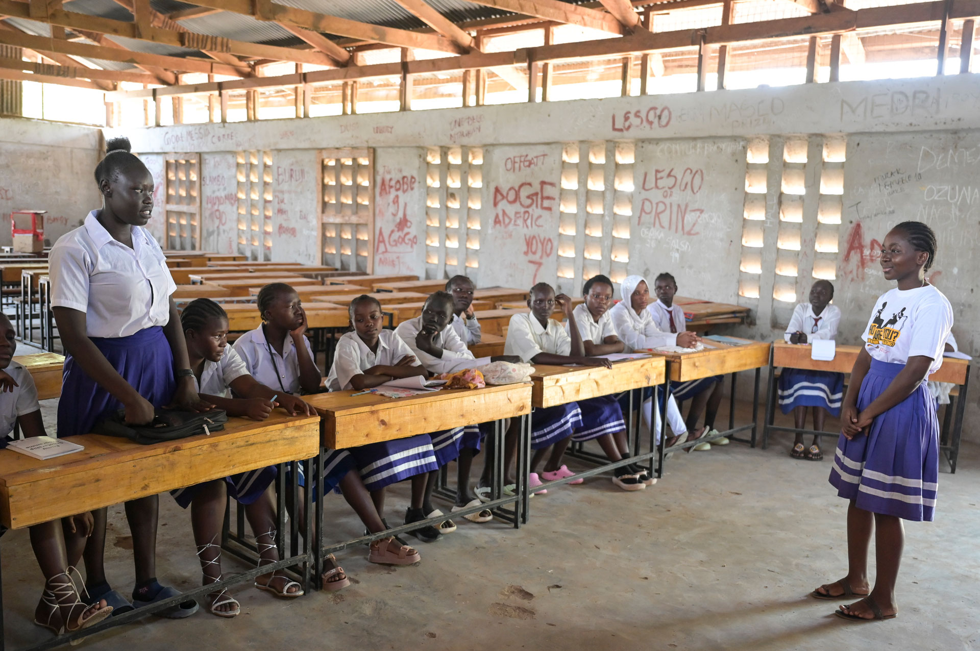 Blick in eine Schule im Flüchtlingscamp Kakuma in Kenia. Zwei junge Frauen blicken sich im einfach eingerichteten Klassenraum an