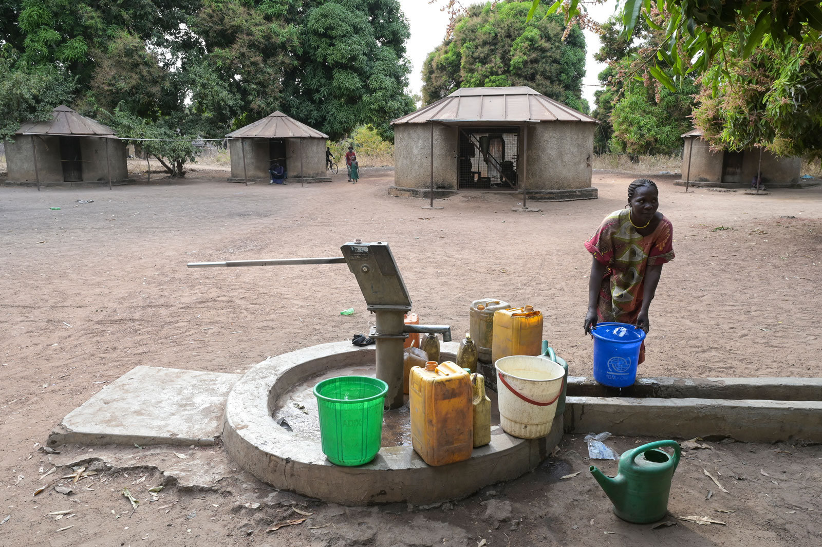 Ein Mann steht vorne, im Hintergrund sind drei Hütten mit Vordach zu sehen