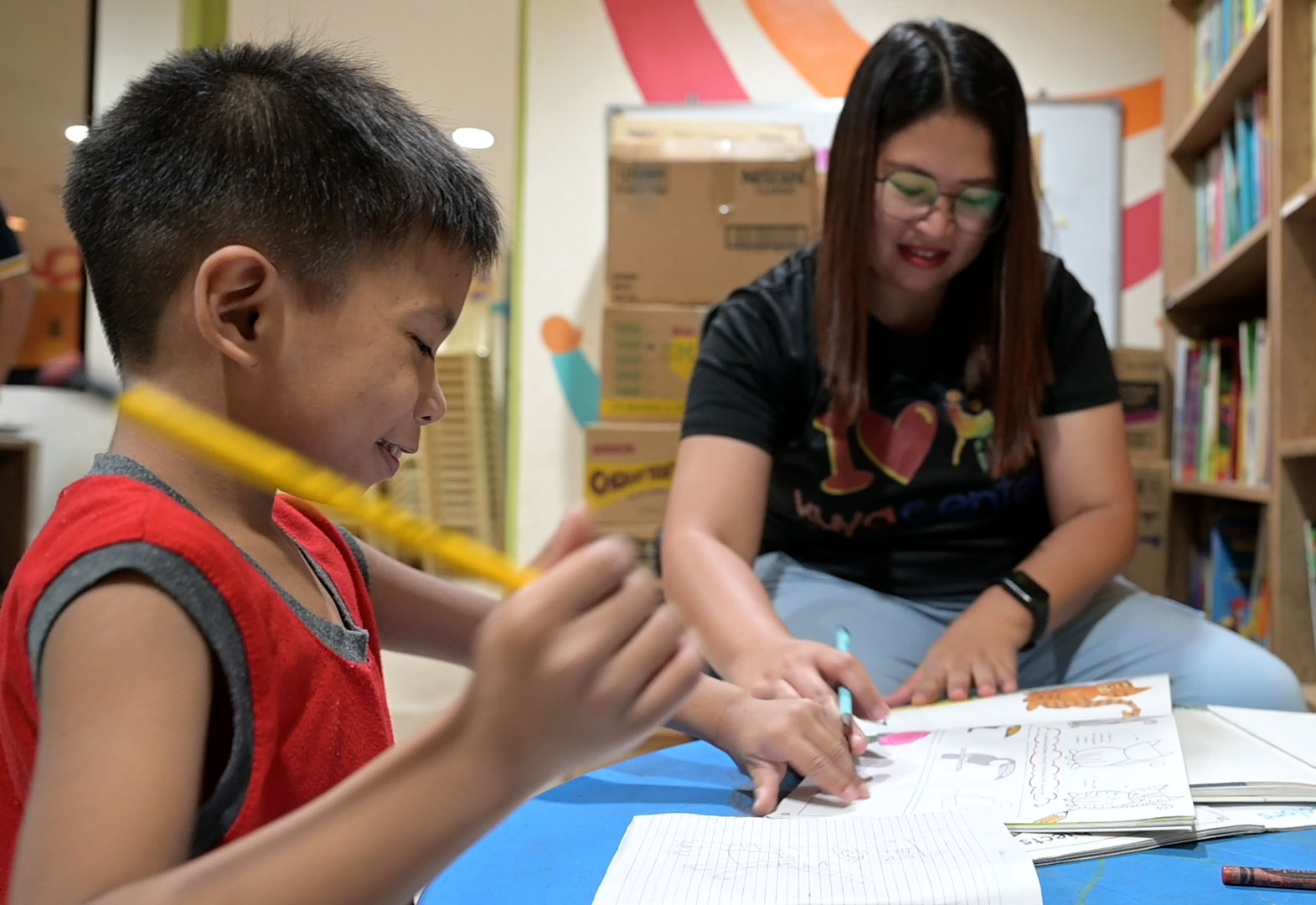Ein Junge und eine Betreuerin sitzen über Schulheften