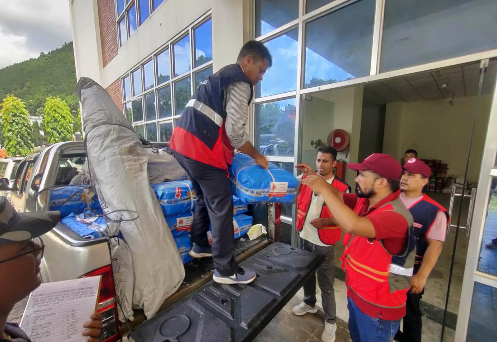 Hilfsgüter der Caritas Nepal werden vor einem intakten Gebäude abgeladen