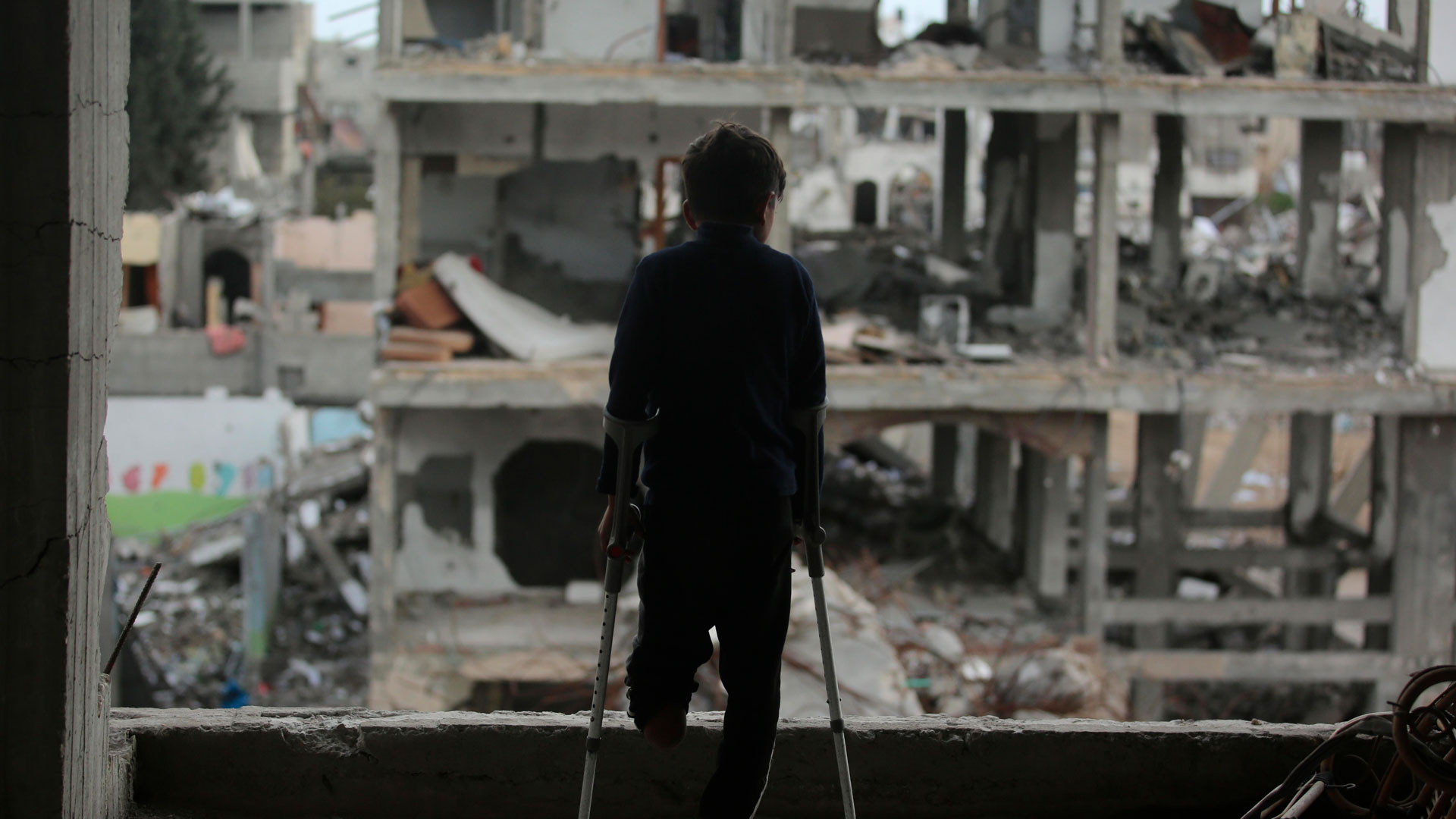 Ein Junge aus Gaza mit amputiertem linken Bein blickt auf Ruinen 