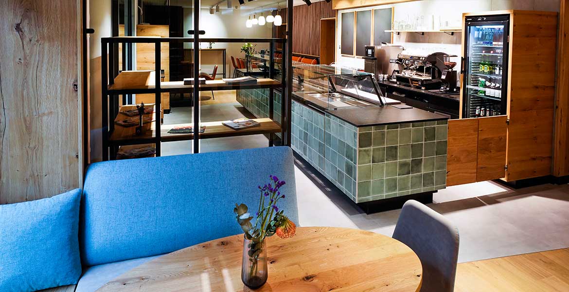 Innenansicht Cafébar Conviva im Haus der Weltkirche. Blick über eine Sitzgruppe auf die Theke.