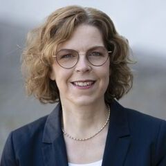 Porträt von Sabine Russling. Sie trägt einen Blazer, hat eine Brille und gewelltes, etwa schulterlanges dunkelblondes Haar.