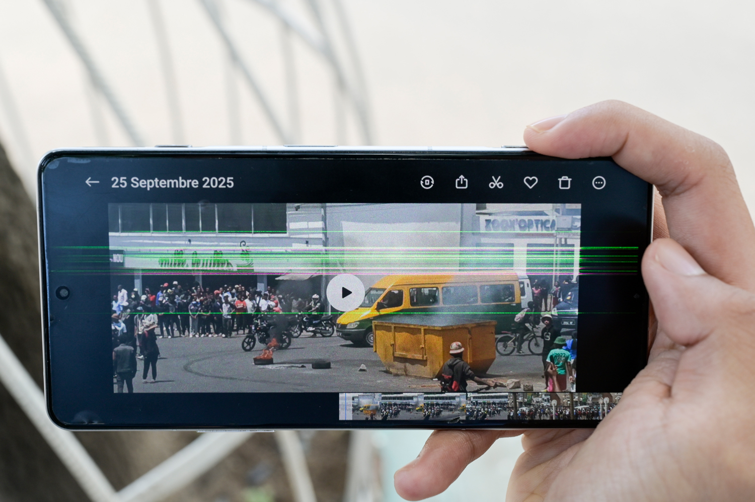Ein Handy, gehalten von einer Hand zeigt im Querformat die Vorschau eines Videos vom 25. September 2025. ZU sehen ist eine Straßenszene mit Feuerschale auf einer Kreuzung. Der normale Verkehr geht während der Proteste weiter.