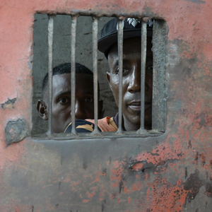 Zwei Gefangene aus Madagaskar blicken aus einem kleinen vergitterten Fenster nach draußen.