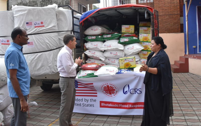 Ein kleiner Lastwagen vollbeladen mit Lebensmitteln steht auf dem Hof der Caritas Nepal in Kathmandu. Davor zwei Helfer der Caritas und Caritas-Direktorin Schwester Cecilia.