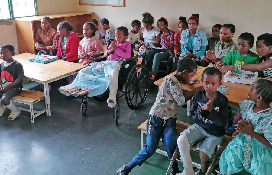 Rund 20 Kinder aus Äthiopien sitzen in einem Klassenraum an Tischen und dazwischen und blicken nach vorne Richtung Kamera.