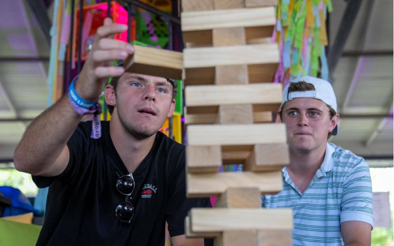 Zwei junge Männer bauen einen Holzturm aus Jenga-Steinen.
