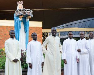 Gruppenfoto von sechs Priesteramtskandidaten in Uganda, alle in weiß gekleidet.