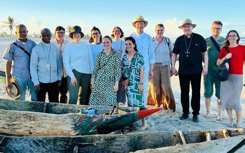 Gruppenfoto der missio-Delegation auf einem Strand in Madagaskar. Im Vordergrund mehrere einfache Boote aus Holz.