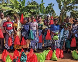 Father Gratian gemeinsam mit einer großen Gruppe von Frauen aus Gemeinden der Diözese Ngara. Er hat zuvor Saatgut an sie ausgegeben, das sie dann zuhause auf ihren Feldern aussäen können.