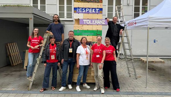 Ein Gruppenfoto mit missio-Mitarbeitenden und Präsident Monsignore Huber rund um einen Holzturm der missio-Demokratieaktion.