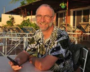 Der in Mali entführte Afrikamissionar Hajo Lohre sitzt an einem Tisch und hat sein Handy in der Hand. Die Sonne steht tief und scheint ihm ins Gesicht. Er blickt den Betrachter an und lächelt. Foto: Raphael Athens