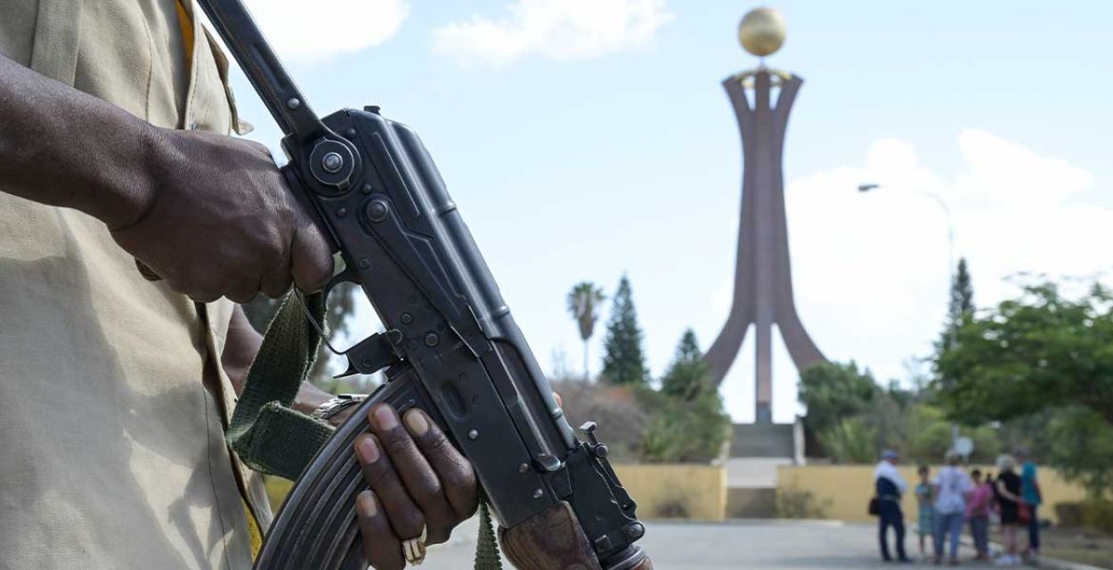Im Vordergrund links im Bild sind die Hände eines Soldaten zu sehen, der ein Maschinengewehr hält. Im Hintergrund das Wahrzeichen der Stadt Mekele in Tigray/Äthiopien: Das Denkmal der Märtyrer.