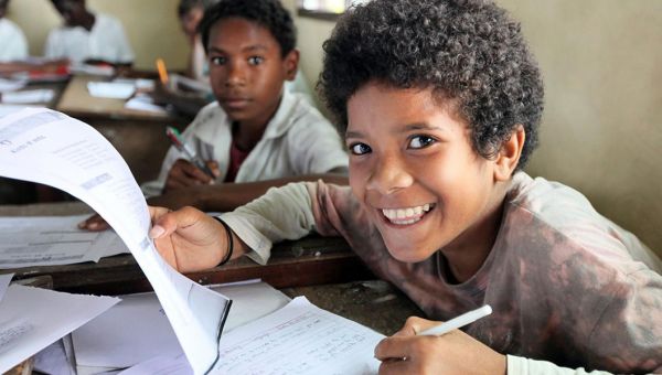 Ein Junge auf Papua-Neuguinea blickt lächelnd von seinen Schulunterlagen auf