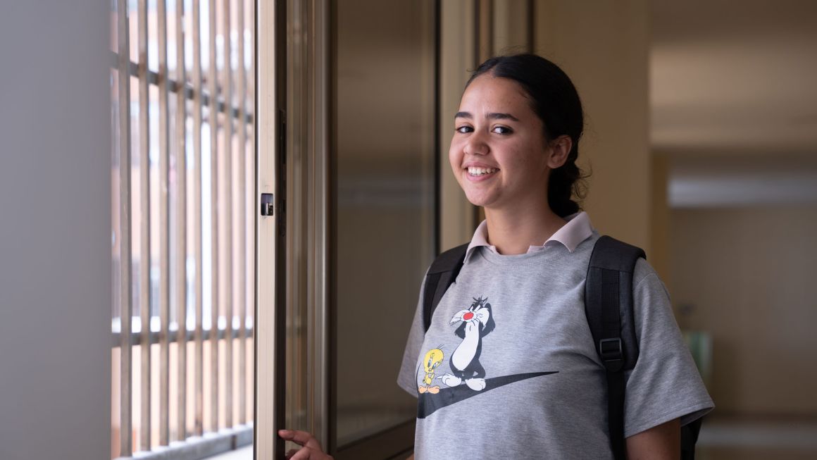 Das Mädchen Sophie aus Damaskus steht an einem Fenster der Schule und lacht