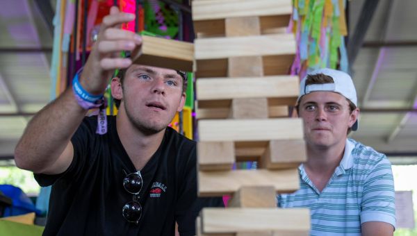 Zwei junge Männer bauen einen Holzturm aus Jenga-Steinen.