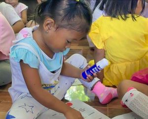 Kinder spielen auf dem Fußboden sitzend in der Kinderhilfseinrichtung von ANCE auf den Philippinen.