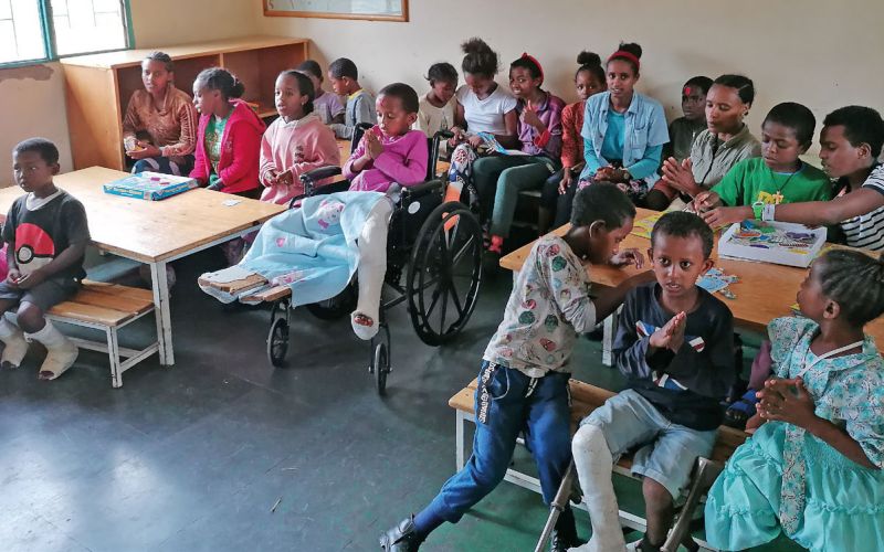 Rund 20 Kinder aus Äthiopien sitzen in einem Klassenraum an Tischen und dazwischen und blicken nach vorne Richtung Kamera.