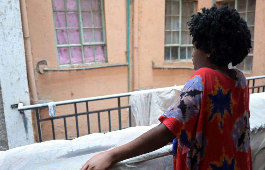 Eine Überlebende von Menschenhandel steht auf einem Balkon in Kenia. Sie ist nur von hinten zu sehen.