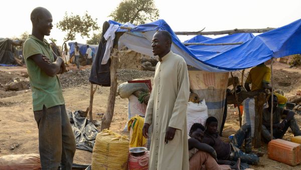 Ein Priester und ein weiterer Mann aus einem afrikanischen Land stehen vor einem provisorischen Zelt.