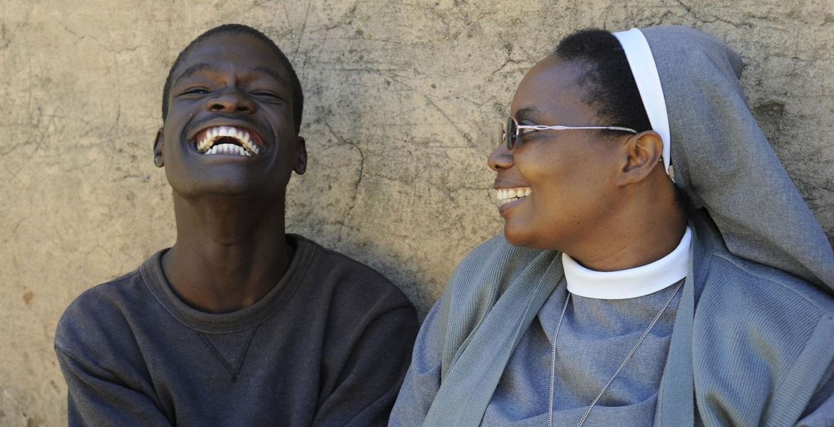Eine Schwester lächelt einen lachenden Mann aus Sambia an 