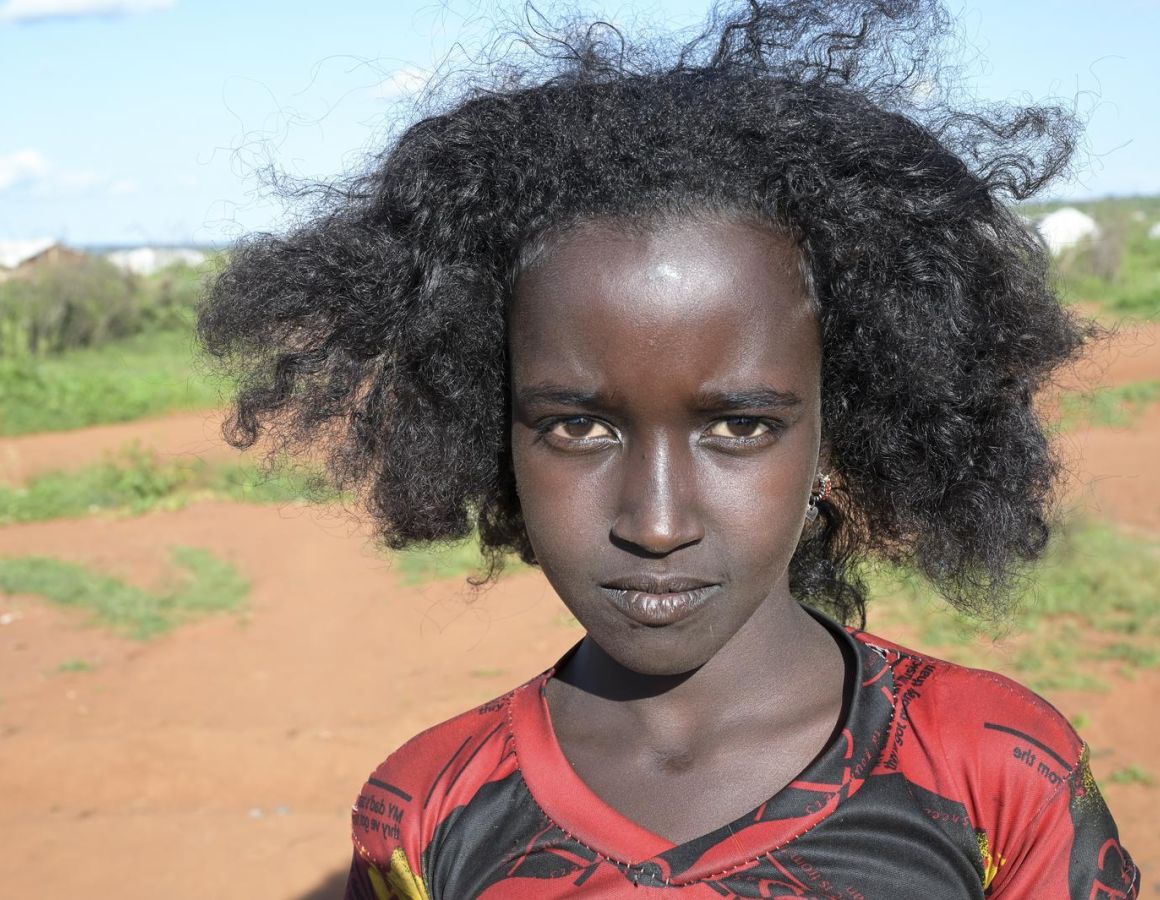 Ein Mädchen aus Äthiopien steht vor karger Landschaft