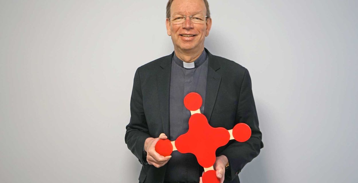 missio-Präsident Monsignore Wolfgang Huber hält das missio-Kreuz aus Holz vor sich.