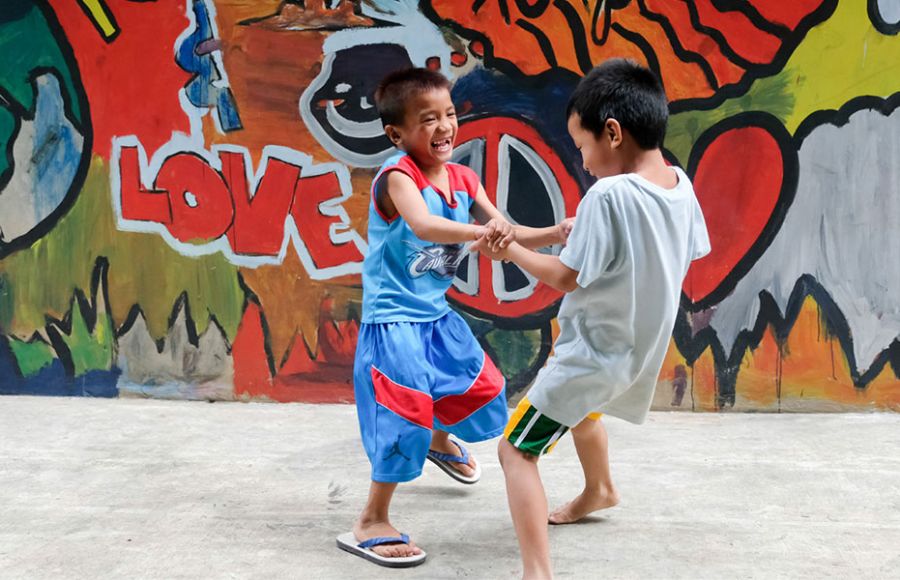Zwei Jungen spielen im Kuya Center in Manila vor einer Grafifti-Wand.