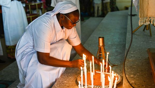 Weltweite Gebetsgemeinschaft: Eine Ordensschwester zündet in Mali Kerzen an