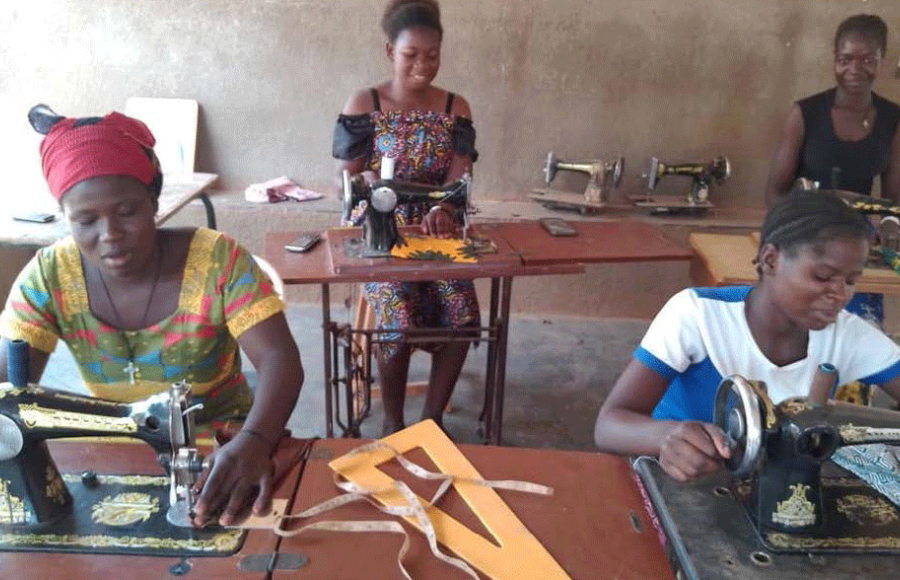 Vier Frauen sitzen in einem Raum des Frauenhauses Sainte Maria Goretti vor Nähmaschinen und nähen.