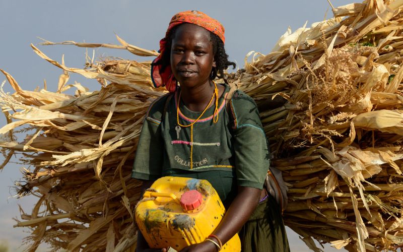 Eine Frau trägt Getreide auf dem Rücken.