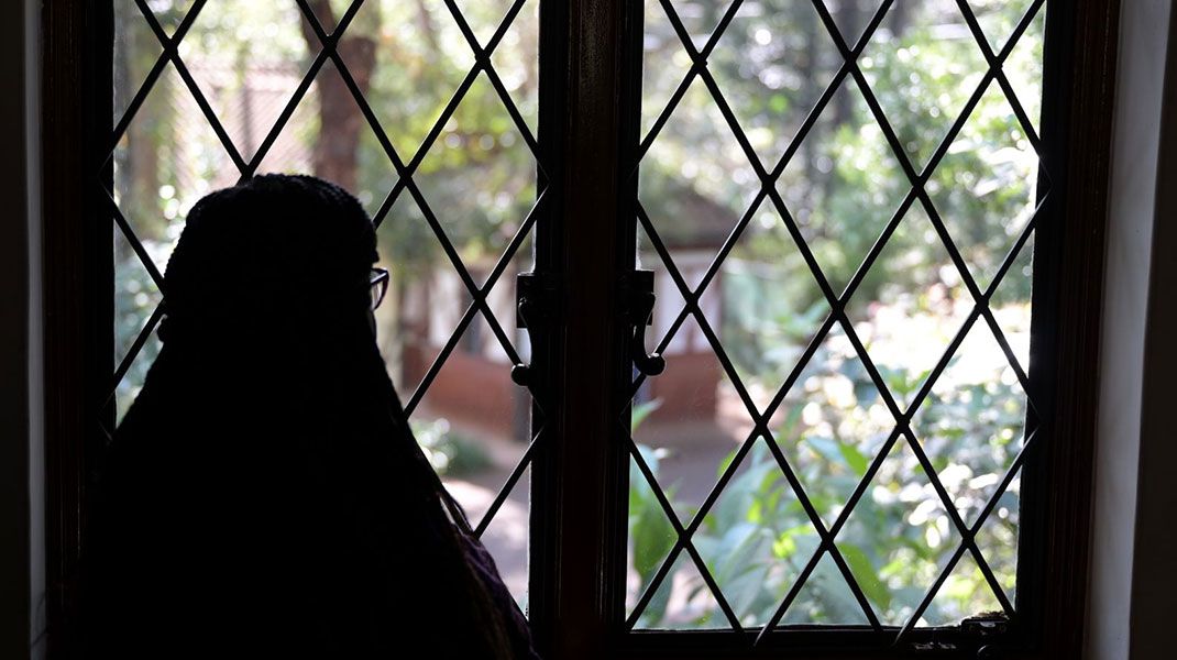 Eine Frau blickt aus einem vergitterten Fenster - Symbolbild Menschenhandel