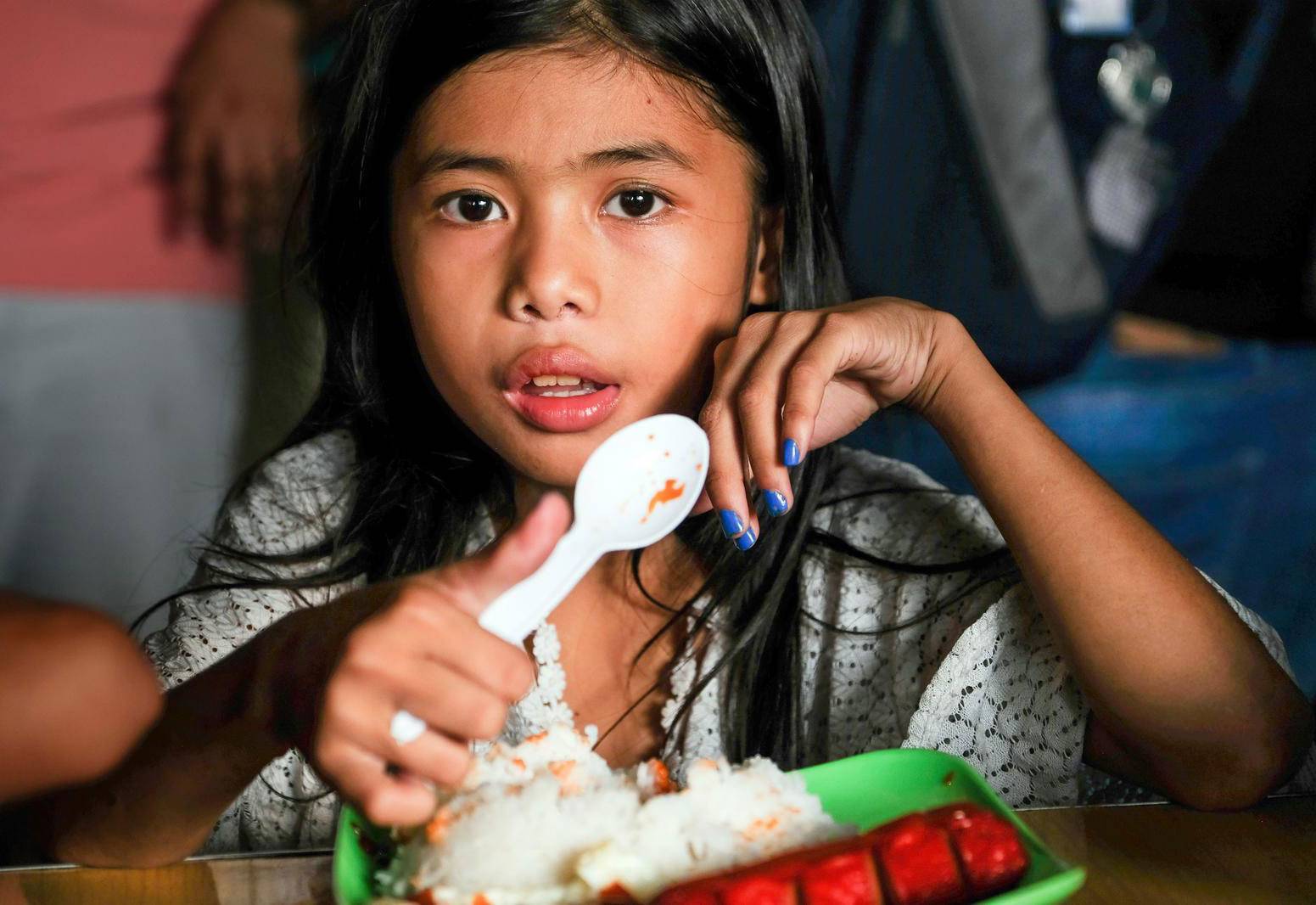 Ein Mädchen aus den Philippinen hat Reis vor sich stehen