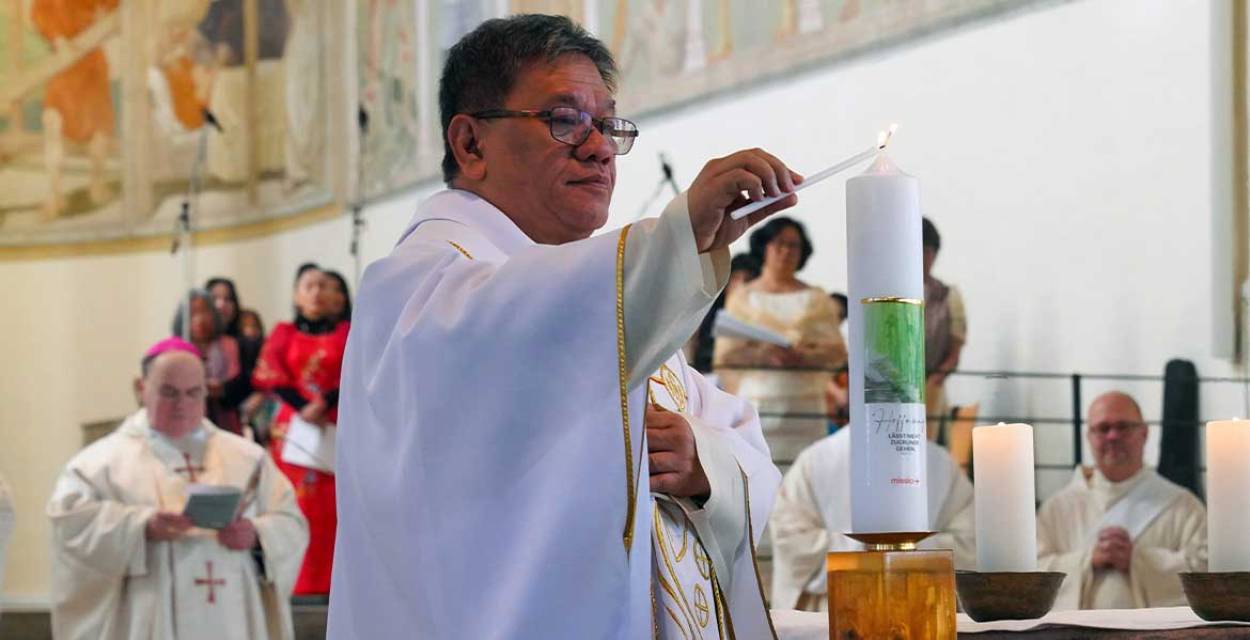 Zu sehen ist der philippinische Priester und Menschenrechtsaktivist Christian "Toots" Buenafe, der beim Gottesdienst zum Sonntag der Weltmission in der Stadtpfarrkirche St. Josef in Memmingen die Kerze zum Weltmissionsmonat entzündet.