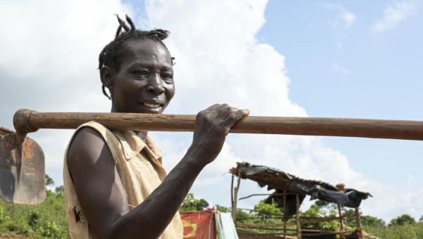 Die Frau vom Titelbild des missio magazin 4/2025, Rose Nanteza, trägt eine Hacke über der Schulter. Sie befindet sich in ihrem neu angelegten Garten auf der Insel Buvuma im Süden von Uganda. Im Hintergrund ist eine einfache Hütte zu sehen.
