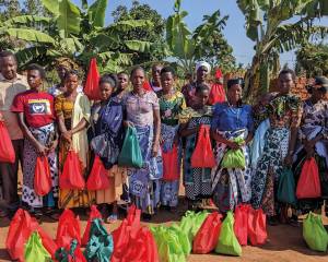 Father Gratian gemeinsam mit einer großen Gruppe von Frauen aus Gemeinden der Diözese Ngara. Er hat zuvor Saatgut an sie ausgegeben, das sie dann zuhause auf ihren Feldern aussäen können.