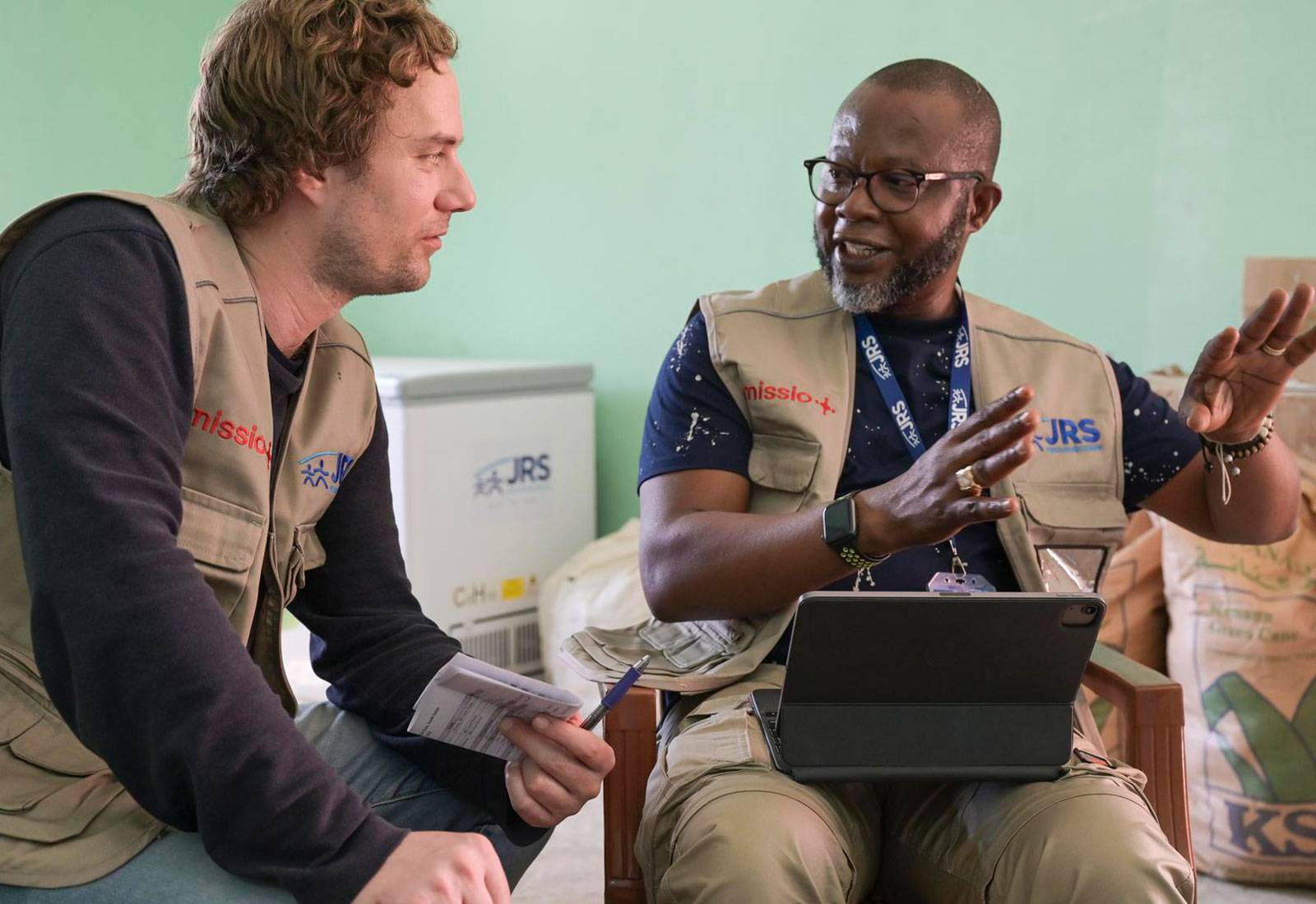 missio-Mitarbeiter Philipp Stangl hört aufmerksam nach vorne gebeugt zu, was André Atsu Agbogan vom JRS ihm erklärt.