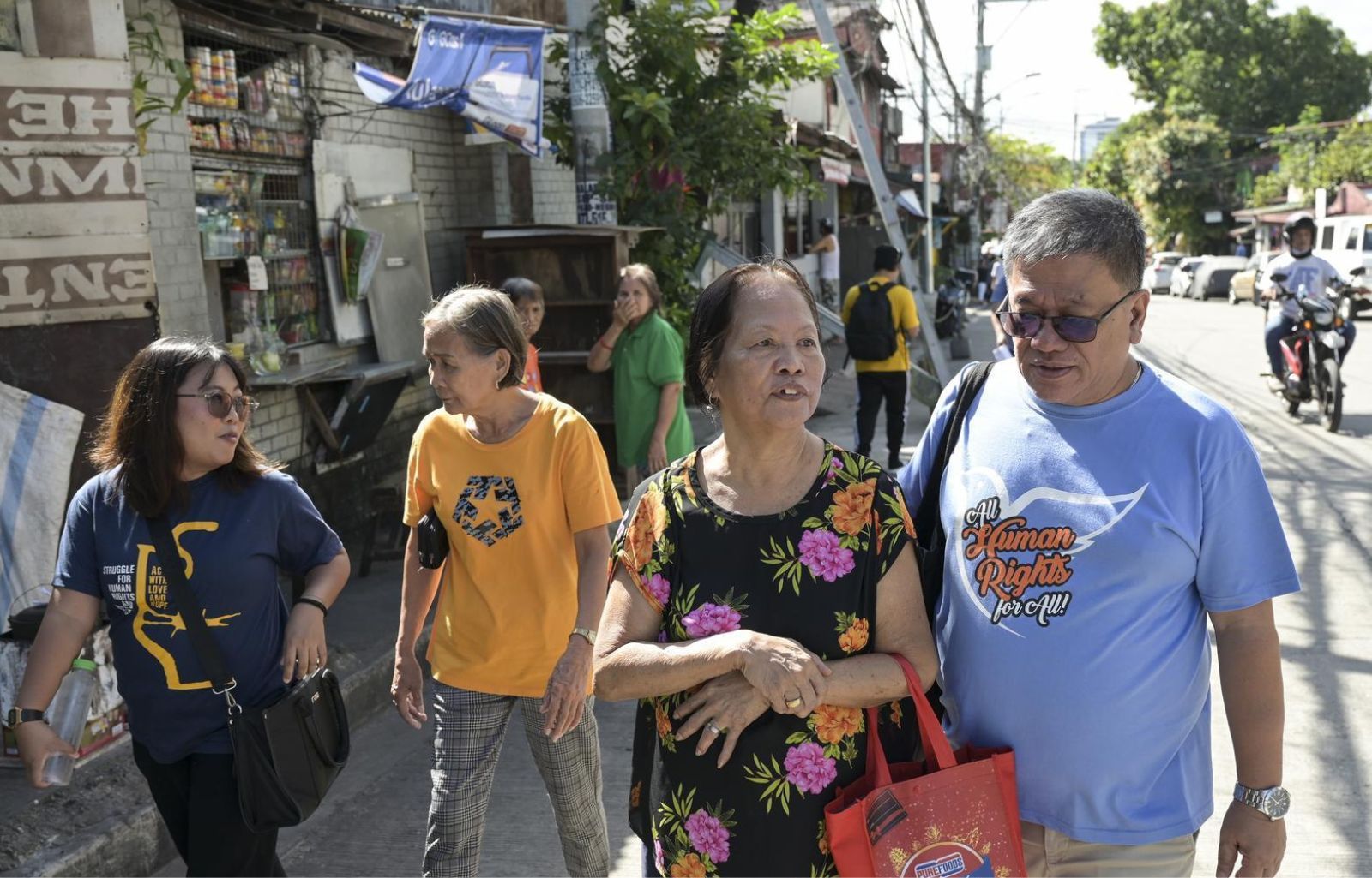 Fr. Christian Buenafe, auch Fr. Toots genannt, geht mit Frau DieDiedurch eine belebte Straße in Quezon City.