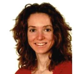 Porträt Deborah Wiegert. Die junge Frau hat eine rote Bluse an und trägt das dunkle, wellige Haar offen und lächelt in die Kamera.