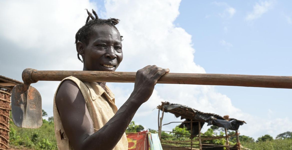 Die Frau vom Titelbild des missio magazin 4/2025, Rose Nanteza, trägt eine Hacke über der Schulter. Sie befindet sich in ihrem neu angelegten Garten auf der Insel Buvuma im Süden von Uganda. Im Hintergrund ist eine einfache Hütte zu sehen.
